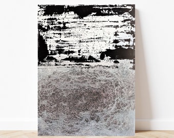 Könnte beinhalten: Abstraktes Kunstwerk mit einem strukturierten schwarzen und weißen oberen Bereich und einem strukturierten grauen und silbernen unteren Bereich. Das Kunstwerk wird vor einer weißen Wand präsentiert und steht auf einem Holzboden.