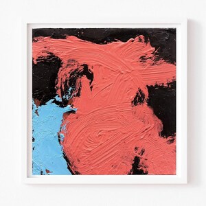 May include: Abstract painting in a white frame. The artwork features bold brushstrokes of coral, black, and light blue. The coral strokes dominate the center, with black at the top and light blue on the left.