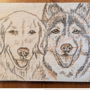 May include: A rectangular light-colored wooden plaque featuring a detailed pyrography portrait of two dogs. The left dog resembles a golden retriever, while the right dog has markings similar to a husky. Both animals are depicted with open mouths.