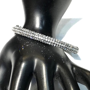 Pulsera articulada de metal oscuro con incrustaciones de diamantes de imitación transparentes y brillantes.