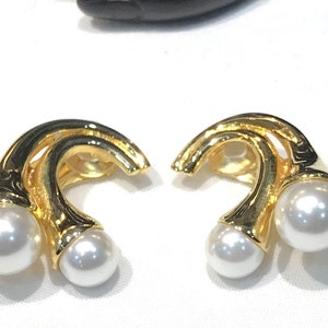 May include: A pair of gold-tone clip-on earrings with two white pearls on each earring.