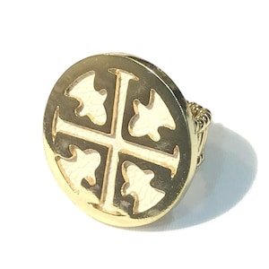 May include: A gold-toned ring with a white enamel design of a cross with four fleur-de-lis. The ring is adjustable.