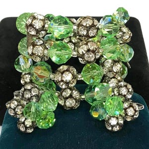 May include: A multi-strand bracelet featuring alternating lime green faceted crystal beads and spherical metal beads encrusted with small clear rhinestones. The design consists of several rows of beads connected to form a wide, flexible cuff-style piece.