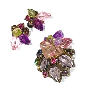 May include: A set of vintage earrings and a brooch. The jewellery features a floral design with colourful, faceted beads in shades of pink, purple, green, and brown. The earrings and brooch are set against a white background.