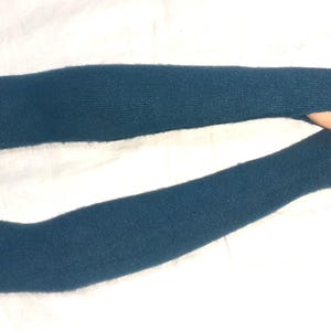 Puede incluir: Un par de calentadores de brazo sin dedos de color azul teal hechos de un tejido de punto suave.