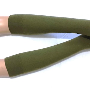 Puede incluir: Guantes sin dedos de color verde oliva. Los guantes son largos, cubriendo los brazos hasta justo debajo del codo. Los guantes tienen un agujero para el pulgar y están hechos de un material suave y elástico. Los guantes se muestran en un maniquí.