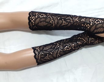 May include: Black lace fingerless gloves with an intricate floral pattern. The gloves are long, extending up the arm, and are displayed on a mannequin hand. The lace has a scalloped edge.