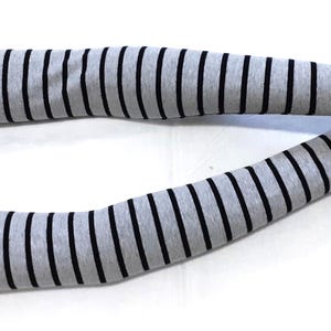 May include: Gray and black striped arm warmers. These fingerless gloves are made of a soft material and feature a classic striped pattern. The arm warmers are designed to cover the arms from the wrist to the upper arm.