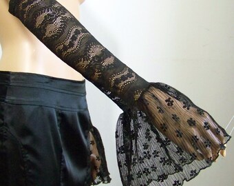 May include: Black lace elbow-length gloves with a wide, ruffled cuff. The gloves are made of a delicate, sheer fabric and have a floral pattern.