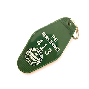 May include: Green plastic hotel key tag with the text "The Berkshires" and the number "413". The key tag has a circular logo that says "Drop in any mailbox. We guarantee postage."