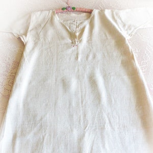 May include: A white linen shirt with short sleeves and a button-up neckline. The shirt has a simple design and is made of a lightweight fabric.