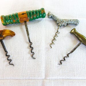 May include: Four vintage corkscrews with varied handle designs. One has a green and wood handle, another a silver horse-shaped handle, and two have curved handles in amber and gold tones. The corkscrews have metal spirals.