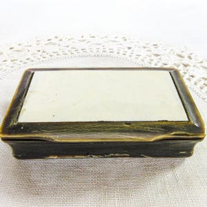 May include: A small, rectangular box with a dark brown wooden exterior and a white interior. The box has a hinged lid and is made of wood.