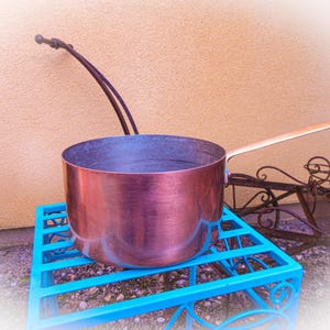 May include: A white ceramic mug with a black handle and the text "But First, Coffee" in a bold, black font. The mug is set against a blurred background, suggesting a cozy setting.