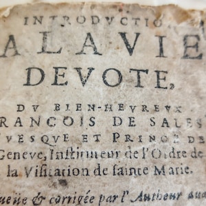 Op de afbeelding: Close-up van een vintage boekomslag met de titel "Inleiding tot het vrome leven" van Frans van Sales, bisschop van Genève. De tekst is in het Frans.