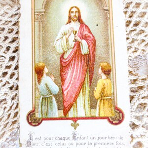 Puede incluir: Tarjeta religiosa vintage con una ilustraci&oacute;n de Jes&uacute;s sosteniendo un c&aacute;liz, flanqueado por dos ni&ntilde;os. La imagen est&aacute; enmarcada con bordes ornamentados e incluye texto en franc&eacute;s en la parte inferior. Los colores son suaves, con rojos, blancos y dorados.