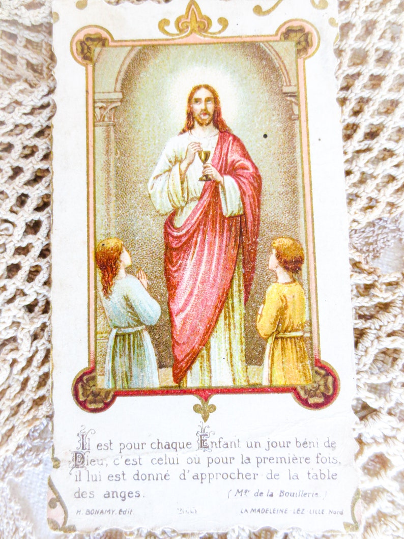 Puede incluir: Tarjeta religiosa vintage con una ilustraci&oacute;n de Jes&uacute;s sosteniendo un c&aacute;liz, flanqueado por dos ni&ntilde;os. La imagen est&aacute; enmarcada con bordes ornamentados e incluye texto en franc&eacute;s en la parte inferior. Los colores son suaves, con rojos, blancos y dorados.