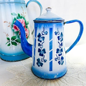 May include: A white ceramic mug with a black handle and the text "But First, Coffee" in a black, handwritten-style font. The mug is on a white surface.