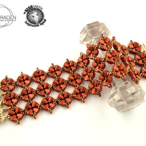 Op de afbeelding: Een bruin en gouden kralenarmband met een geweven sluiting. De armband is gemaakt met kleine, gefacetteerde kralen en heeft een geometrisch patroon.