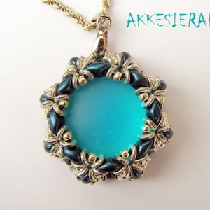 May include: A teal blue pendant necklace with a silver chain and a round, teal blue glass cabochon surrounded by a silver and dark teal bead border.