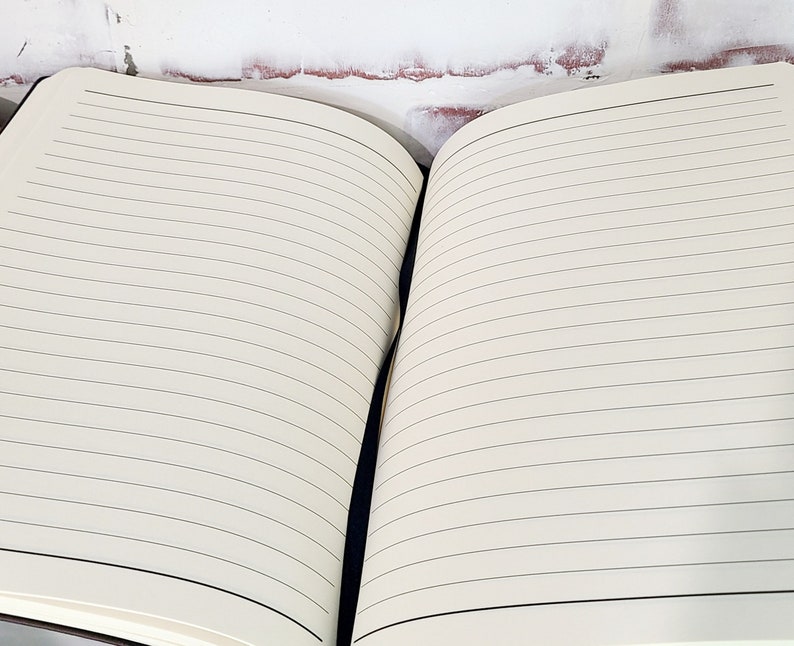 Pu&ograve; includere: Quaderno aperto con pagine a righe color crema. Le pagine hanno sottili linee nere orizzontali. Il quaderno &egrave; aperto, rivelando le pagine interne. La rilegatura &egrave; scura e le pagine sono pulite e pronte per la scrittura.
