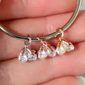 Puede incluir: Tres colgantes de amuleto con piedras de circonita c&uacute;bica transparentes. Los amuletos son de plata, oro rosa y oro.