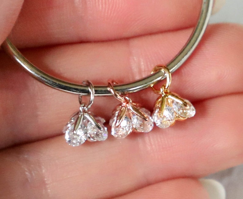 Puede incluir: Tres colgantes de amuleto con piedras de circonita c&uacute;bica transparentes. Los amuletos son de plata, oro rosa y oro.