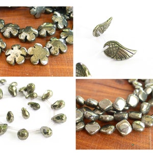 May include: Three strands of pyrite beads in different shapes and sizes. The first strand features flower-shaped beads, the second strand features teardrop-shaped beads, and the third strand features square-shaped beads. The beads are a metallic silver color with a slight gold sheen.