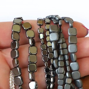 以下が含まれることがあります： さまざまなグレーの色合いの正方形のビーズのコレクション。ビーズは金属やガラスなど、さまざまな素材で作られています。ビーズは糸に通されており、ジュエリー作りに使用できます。