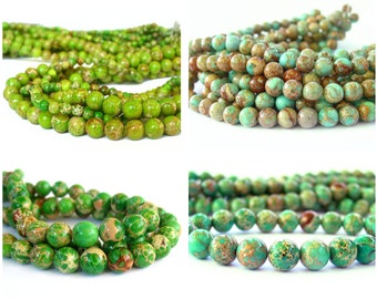 Puede incluir: Primer plano de hilos de cuentas de piedras preciosas verdes y marrones. Las cuentas redondas tienen un aspecto moteado, con patrones marrones y beige. Las cuentas están ensartadas, listas para la creación de joyas.