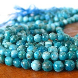 May include: A strand of blue apatite beads. The beads are round and have a smooth, polished finish. The beads are strung on a clear thread.