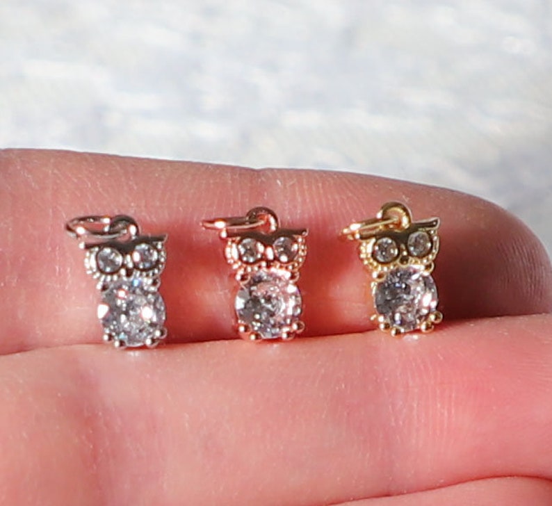 Puede incluir: Tres dijes de b&uacute;ho con detalles de cristal transparente. Los dijes son de plata, oro rosa y oro.