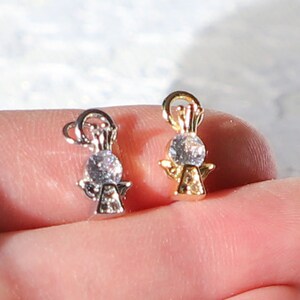 Puede incluir: Dos abalorios de &aacute;ngel con un cristal transparente en el centro. Un abalorio es dorado y el otro es plateado.