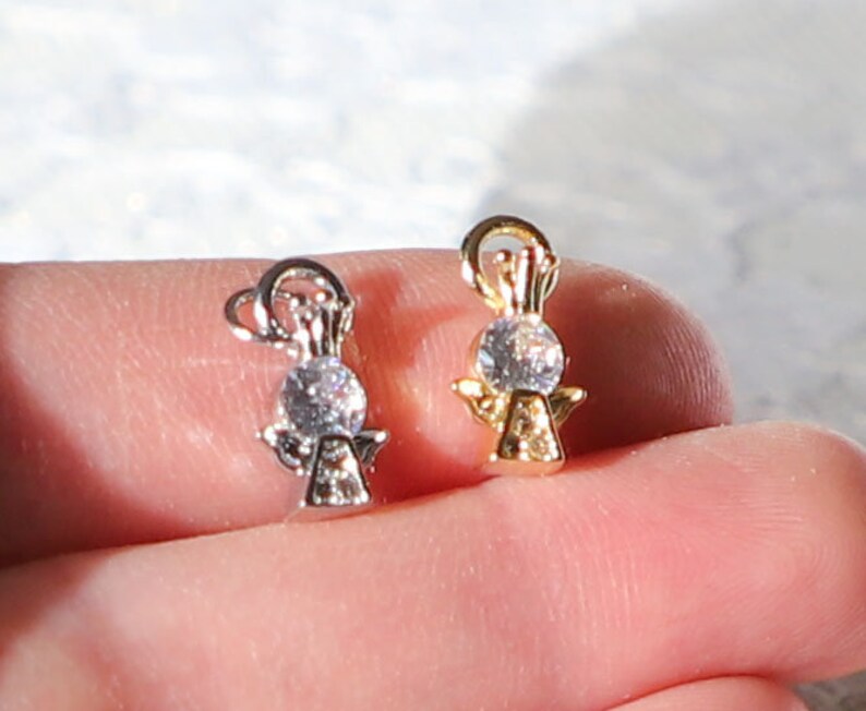 Puede incluir: Dos abalorios de &aacute;ngel con un cristal transparente en el centro. Un abalorio es dorado y el otro es plateado.