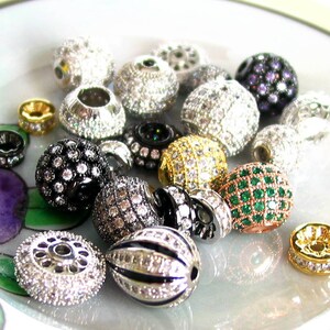 Puede incluir: Surtido de cuentas redondas y ovaladas con varios colores y dise&ntilde;os. Las cuentas est&aacute;n adornadas con diamantes de imitaci&oacute;n transparentes y de colores. Algunas cuentas tienen un acabado plateado u dorado.