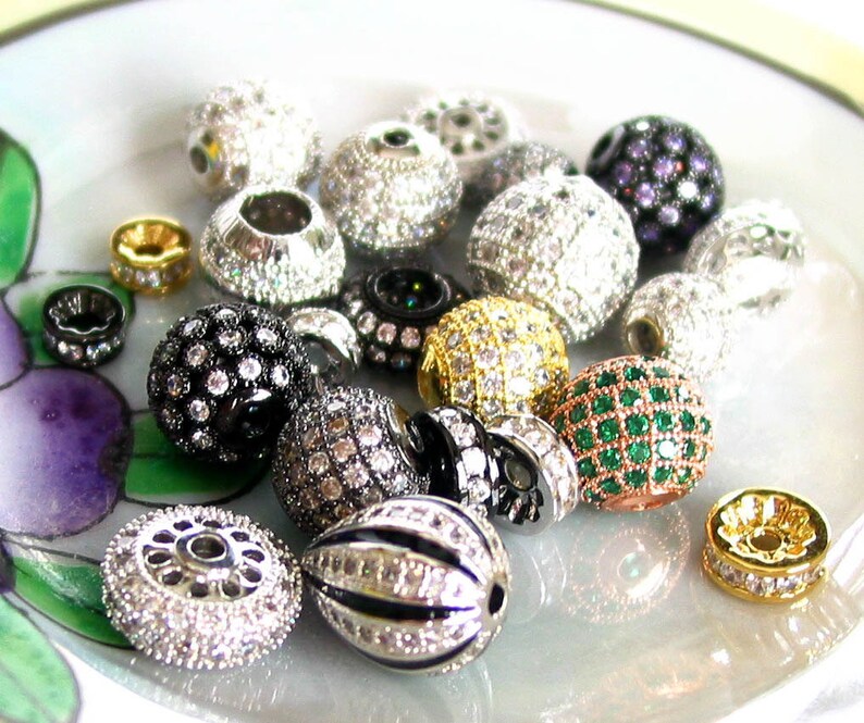 Puede incluir: Surtido de cuentas redondas y ovaladas con varios colores y dise&ntilde;os. Las cuentas est&aacute;n adornadas con diamantes de imitaci&oacute;n transparentes y de colores. Algunas cuentas tienen un acabado plateado u dorado.