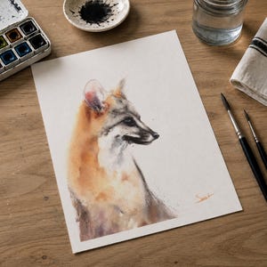 May include: A watercolor painting on white paper depicting a fox in profile, rendered in shades of orange, brown, and grey. The artwork features a soft, blended style with visible brushstrokes and a small orange signature in the bottom right corner.