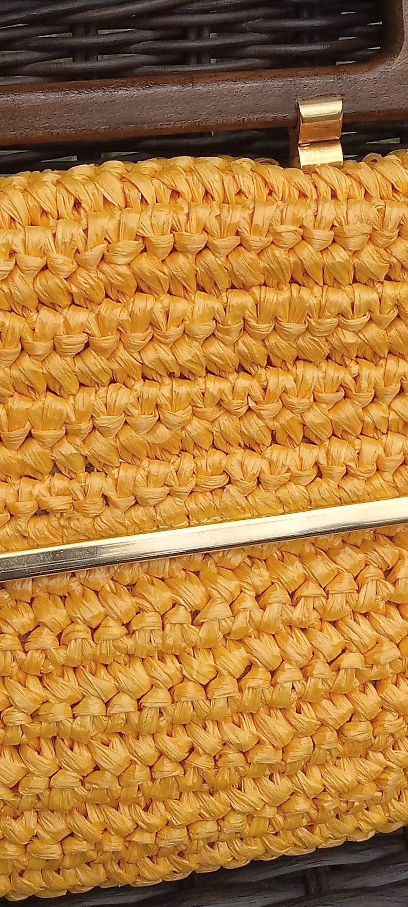 Pode incluir: Close-up de uma bolsa amarela tecida com um fecho de metal dourado. A bolsa &eacute; feita de um material tecido apertado, criando uma superf&iacute;cie texturizada.