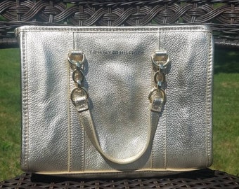 Może przedstawiać: Złota skórzana torba typu tote z łańcuszkowym paskiem i napisem "Tommy Hilfiger" z przodu.