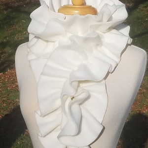 May include: A white ruffled collar made of fleece fabric. The collar is displayed on a white mannequin.