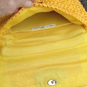 Pode incluir: Clutch de tecido amarelo com fecho dourado e uma etiqueta que diz "Feito na It&aacute;lia, Lorenza".