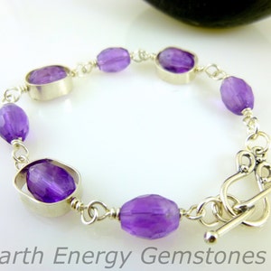 K&ouml;nnte beinhalten: Ein silbernes Armband mit einem Schiebeverschluss zeigt ovale Amethyst-Edelsteine, die in Silber gefasst sind.