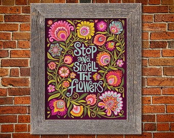 May include: A framed print with a purple background and colorful floral designs. The text "Stop and smell the flowers" is written in a whimsical font.
