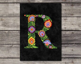 May include: A black background with a large, stylized letter "R" made of colorful flowers and vines. The letter is in a folk art style with bright colors and intricate details.