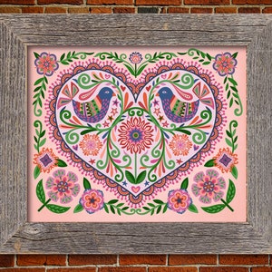May include: A framed print with a pink background featuring a large heart-shaped design with intricate floral patterns, birds, and stars. The heart is surrounded by smaller floral designs in shades of pink, green, and blue.