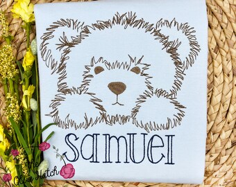 May include: A light blue baby onesie with a brown embroidered cartoon dog and the name "Samuel" embroidered in blue.