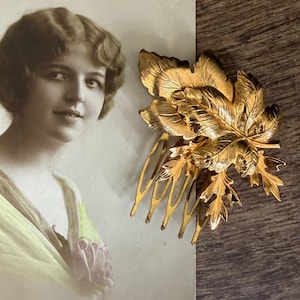 Op de afbeelding: Een vintage ansichtkaart met het woord "Anniversaire" in gouden letters, met een sepia-getint portret van een vrouw. Een goudkleurige haarspeld in de vorm van een blad rust aan de rechterkant en voegt een vleugje elegantie toe. De ansichtkaart heeft de tekst "REX 4985".