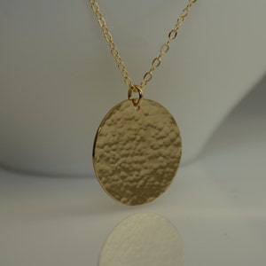 May include: A gold necklace with a large, round, hammered pendant.