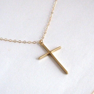 May include: A gold chain necklace with a simple gold cross pendant.