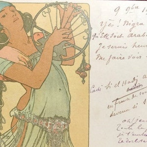 May include: A vintage postcard depicting a woman in a blue turban and a light blue dress holding a large, ornate, metal fan. The postcard is written in French and includes the text "Yes! Nigra est, quell soch Arabe, to Je serais heuren Me faire voir tou Ladi Si el Hady ali be en fra i saze oh/jeannea Zoute la joure jit'embrassuo Zederliterai".